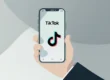 Empresário utilizando celular com o logo do TikTok, representando a aplicação da psicologia do consumo e estratégia de vendas em pequenos negócios.